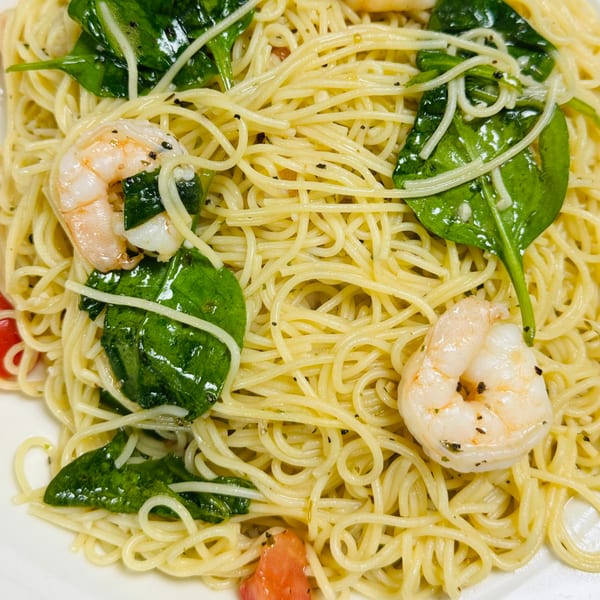 Close-up of Casa D'angelo's shrimp scampi with spaghetti, spinach, and diced tomatoes.