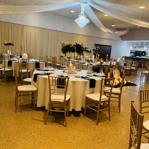 Elegant dining room at Casa D'angelo with round tables, gold chairs, candles, and floral centerpieces.
