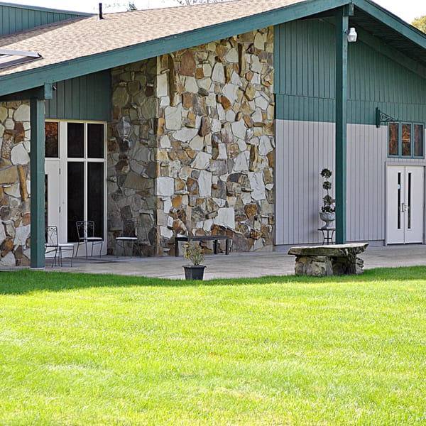 Exterior of Casa D'angelo, featuring stone and green siding, with a lush green lawn in the foreground.